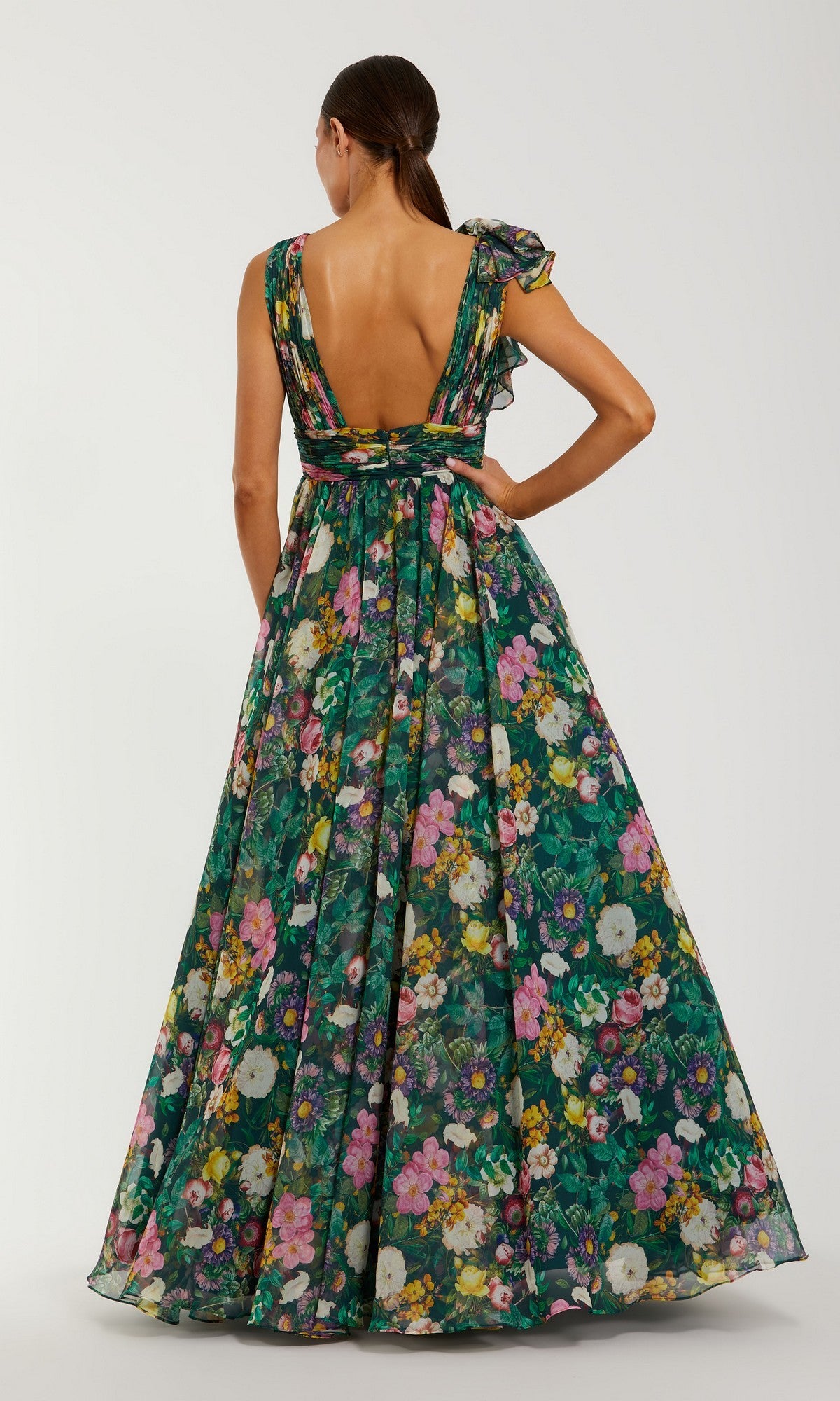 A woman faces away from the camera in the Mac Duggal 68947 Floral-Print Long Formal Dress, a sleeveless gown with an open back and vibrant flower print.